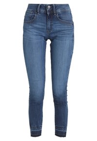 Úzké džíny ze středně modrého denimu s vysokým pasem, pěti kapsami a jemným oděráním. Neopracovaný lem u kotníku.