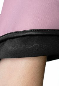 Rosa Stoff mit strukturiertem Finish oben, darunter ein schwarzer Streifen mit geprägtem Text "HEAT CAPTURE SYSTEM".