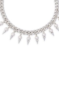 Srebrny naszyjnik łańcuszkowy z przemiennie ułożonymi białymi perłami i spiczastymi metalowymi akcentami, o masywnej konstrukcji i gładkiej fakturze.