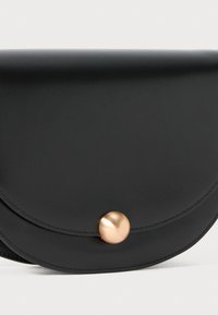 Black leather clutch bag with a smooth texture, rounded envelope design, and a gold circular metal clasp as a closure detail.