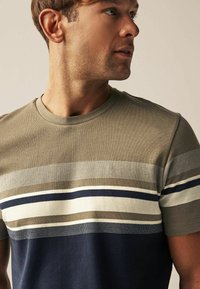 Tricou cu mânecă scurtă, cu guler rotund, secțiuni în verde măsliniu și albastru marin, și dungi orizontale în crem, taupe și albastru. 