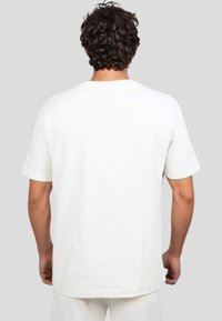 Camiseta de algodón blanca con cuello redondo, mangas cortas y un corte relajado. Presenta una textura suave y un diseño simple sin patrones.