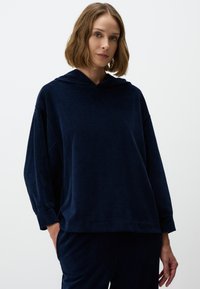 Marineblauwe hoodie met ribbelstructuur, ontspannen pasvorm, doorgeschoven schouders en lange mouwen, in combinatie met bijpassende broek.