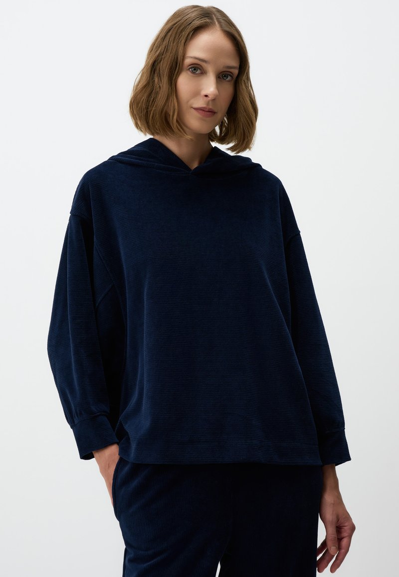 Marineblauwe hoodie met ribbelstructuur, ontspannen pasvorm, doorgeschoven schouders en lange mouwen, in combinatie met bijpassende broek.