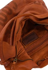 Sac en cuir marron avec une texture douce, comportant une poche intérieure zippée et une étiquette embossée du nom de la marque "VIZINZA."