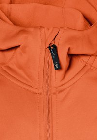 Orange zip-up hoodie med høj krave, med en lynlås og sort stofmærke. Blød tekstur med stikninger på stoffet.