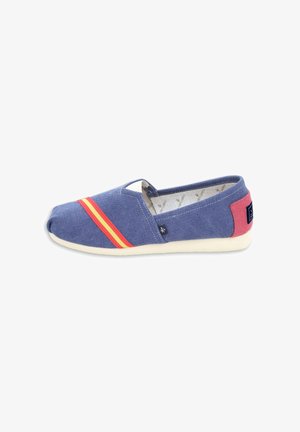 Zapatilla azul de lona tipo slip-on con rayas rojas y amarillas en la parte delantera, parche rosa en el talón, suela blanca y pequeña etiqueta lateral negra.
