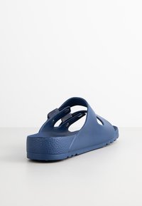 Navy blue slide sandal made of textured rubber. Features cut-out details and a thick, textured sole with a rounded back for comfort.