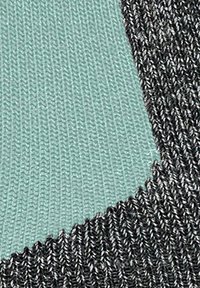 Tessuto lavorato a maglia con una sezione verde menta e una sezione grigio scuro texturizzata, caratterizzato da linee distinte e una consistenza liscia e morbida.