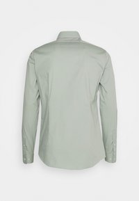 Camicia verde chiaro a maniche lunghe con colletto classico, polsini abbottonati e una texture liscia e opaca. Design semplice senza ulteriori motivi.
