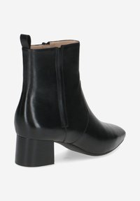 Bottines en cuir noir avec un bout pointu, un talon bloc de hauteur moyenne et une fermeture éclair à l'arrière. Texture lisse avec des accents minimalistes.