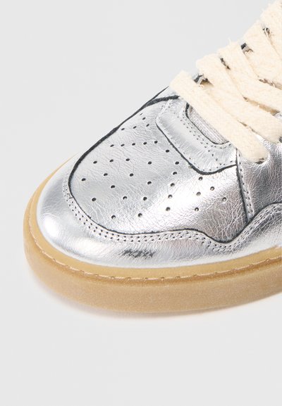 Zapatillas metálicas plateadas con detalles perforados, cordones de color crema y suela de goma, con un acabado de cuero texturizado.