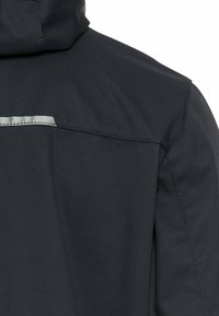 Dunkel gefärbte Jacke aus strukturiertem Stoff mit Kapuze und reflektierendem Akzent über dem Rücken, sauberer Nahtführung und tailliertem Design.