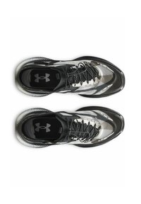 Black and white athletic shoes with textured mesh upper, curved design, and black laces. Features an Under Armour logo on the tongue.