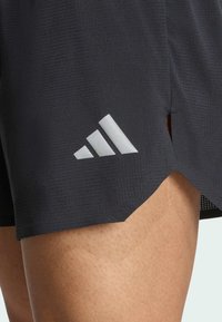 Black athletic shorts with a textured fabric, featuring a silver Adidas logo on the lower side and side slits for ventilation.