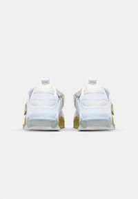 Zapatillas deportivas blancas con parte superior de malla texturizada, suela transparente y acentos de goma amarilla, que cuentan con tiradores en los talones para facilitar su uso.