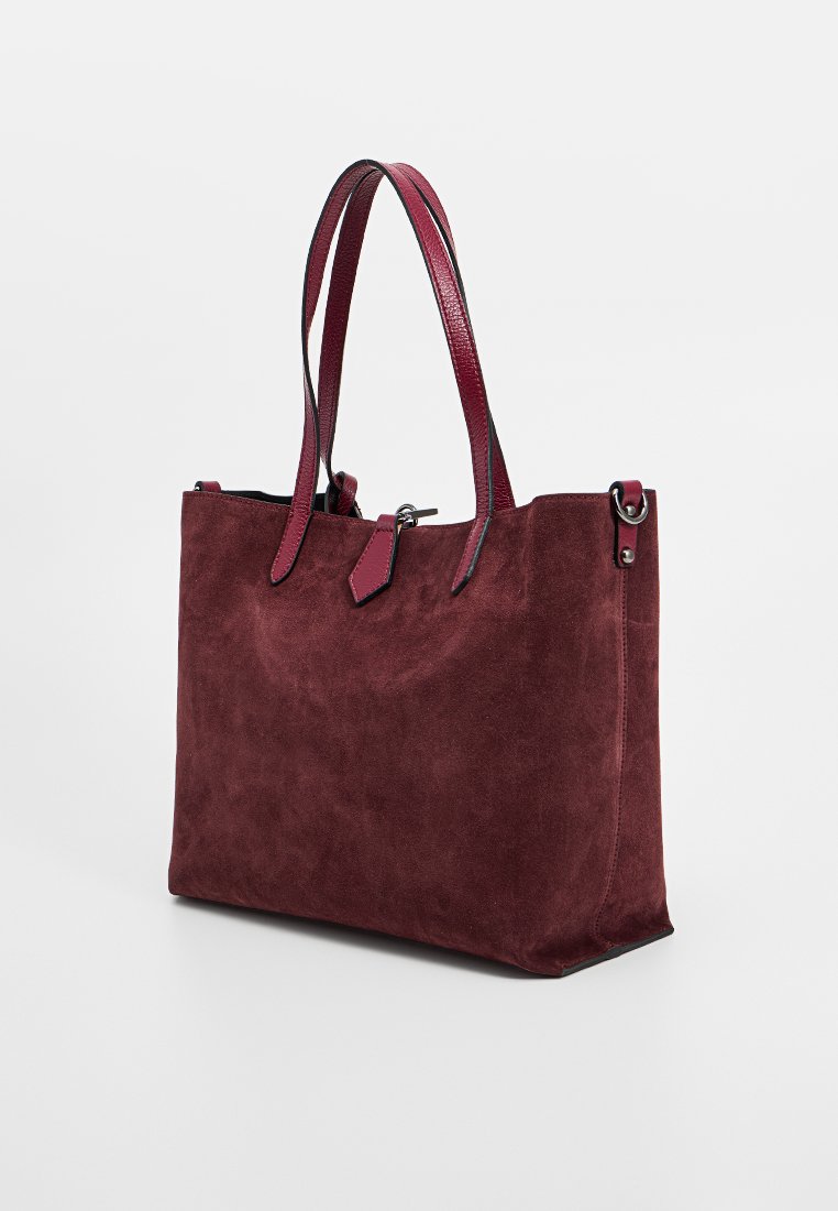 Burgunderfarbene Wildleder-Tote-Bag mit Ledergriffen, die eine glatte Textur, einen offenen oberen Teil und ein minimalistisches Design aufweist. Verstellbare Seitenriemen sind inklusive.