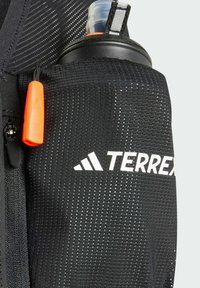Mochila negra con un diseño de malla, que presenta un tirador de cremallera naranja, el logotipo de Adidas Terrex y un bolsillo para botella de agua.