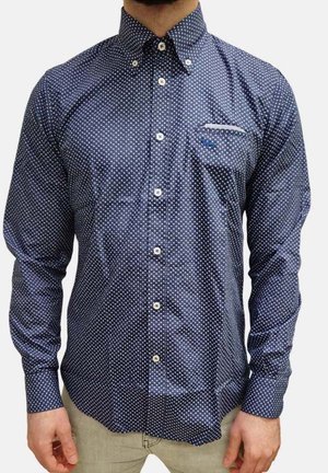 Camicia a maniche lunghe blu navy con pois bianchi, colletto button-down, taschino sul petto e bottoni bianchi sul davanti.