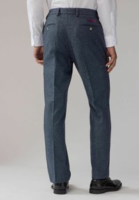 Dunkelblaue Hose mit strukturiertem Finish, ausgestattet mit zwei Gesäßtaschen mit Knöpfen und einem kontrastierenden Akzent an der rechten Tasche.