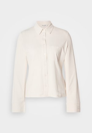 Šviesiai smėlio spalvos ilgomis rankovėmis marškiniai su mygtukais priekyje, apykakle ir viena krūtine kišenė. Pagaminti iš minkštos medžiagos, su rankoves puošiančiais detalėmis.