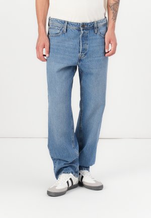 Lyseblå denimjeans med avslappet passform, med fem lommer og knapplukking. Brukt med hvite joggesko.