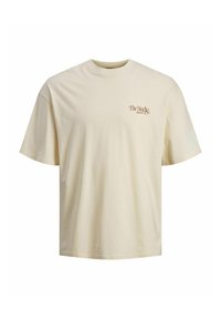 Crème kleurige katoenen t-shirt met korte mouwen, een ronde hals en een klein bruin tekstlogo met de tekst "The Studio" aan de voorkant.