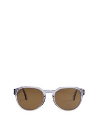 Gafas de sol redondas con montura transparente, lentes marrones y acentos oscuros en las patillas. La montura presenta una textura suave y un diseño minimalista.