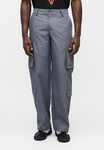 Pantalon cargo gris avec une taille boutonnée, doté de multiples poches, de coutures plates et d'une coupe droite. Tissu texturé avec un motif subtil.
