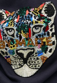 Sudadera negra con un diseño de cabeza de leopardo hecho de cuentas de colores, con texturas intrincadas, cuentas de varios colores y acentos brillantes.