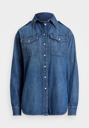 Mėlynas džinsinis marškinis su mygtukų užsegimu, klasikine apykakle ir dviem krūtinės kišenėmis. Turi ilgus rankovės ir apvalią apatinę dalį.