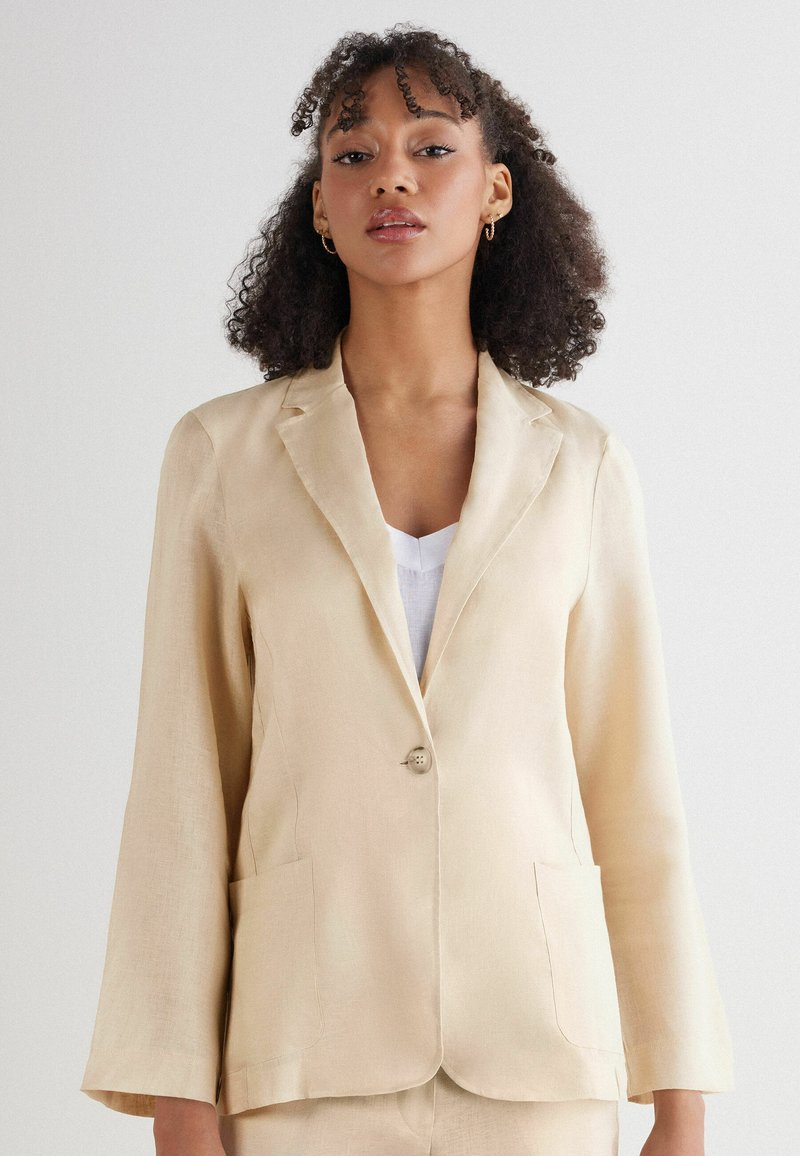 Beige linnen blazer met een enkele knoopsluiting, notch revers, twee voorzakken en lange mouwen, met een gladde textuur.