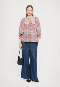 Floral-patterned blouse with balloon sleeves, paired with wide-leg denim pants. A small black woven handbag completes the outfit.