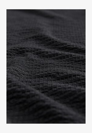 Schwarzer strukturierter Stoff mit einem Rautenmuster, in einer drapierten Position gezeigt. Das Material wirkt weich mit einer leicht unebenen Oberfläche.