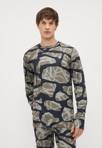 Camisola atlética de mangas longas em tecido elástico, apresentando um padrão de camuflagem em tons de caqui e azul-marinho, com decote redondo.