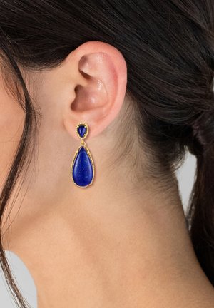 Goldfarbene Tropf Ohrringe mit einem blauen Lapislazuli-Design in Tropfenform, akzentuiert durch einen kleineren ovalen Stein an der Oberseite.