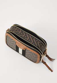 Rektangulär resepåse med två zip-fickor. Bruna geometriska mönster, tannfärgade läderdetaljer, svart och vit rand, guldiga dragkedjor.