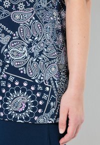 Marinblå topp med paisleymönster i rosa och ljusblått. Mjukt material med synliga stygn och en liten logotags vid fållen.