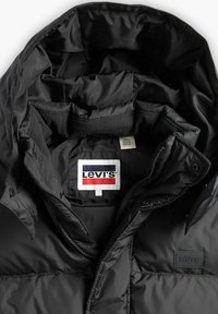 Giacca a vento nera con colletto alto, bottoni a pressione e zip. Presenta un'etichetta con il logo Levi's e una superficie liscia e lucida.
