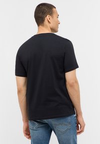 Czarna bawełniana koszulka z krótkim rękawem i okrągłym dekoltem, widoczna z tyłu. Charakteryzuje się gładką fakturą i luźnym krojem.