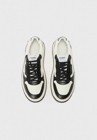 Sorte og cremefarvede lædersneakers med en struktureret overflade, perforerede detaljer, flade snørebånd og en tyk hvid gummi sål. Logo på tungen.