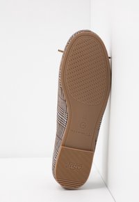 Semelle d'une chaussure plate marron à carreaux avec semelle antidérapante texturée et taille 37 marquée sur fond beige.