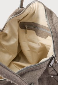 Szare, teksturowane wnętrze torby z beżową podszewką; zawiera kieszeń na zamek oraz zapięcie na zamek. Na szwach widoczne przeszycia krawędzi.