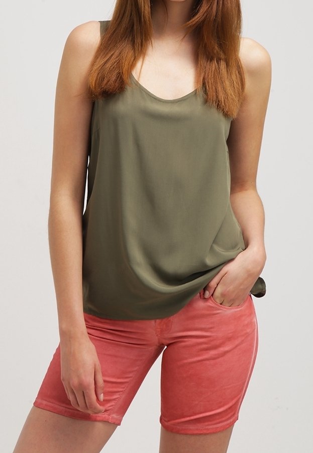 Top senza maniche verde oliva abbinato a pantaloni corti rosa realizzati in un tessuto morbido e texturizzato, caratterizzati da una vestibilità rilassata e tasche laterali.