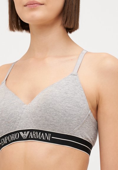 Light gray cotton bralette with adjustable straps and a black elastic band featuring the "Emporio Armani" logo. Smooth texture, simple design.