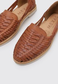 Zapatos de cuero marrón tipo slip-on con diseño trenzado y puntera redonda. Cuentan con una plantilla de color marrón claro y una suela de goma plana para mayor comodidad.