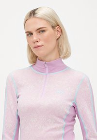 Gaiši violets gara piedurkne krekls ar puszipa apkakli, ziedu tekstūru un kontrastējošām gaiši zilām šuvēm, ar mazu logotipu uz krūtīm.