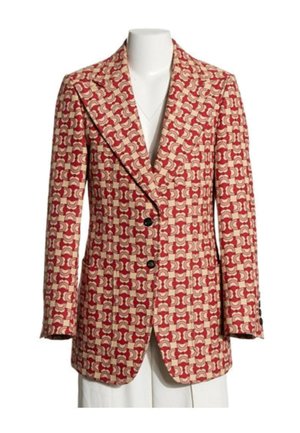 Blazer rouge et beige à motifs avec larges revers, deux boutons noirs et manches longues présenté sur un buste de mannequin blanc.