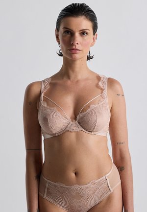 Soutien-gorge nude avec dentelle, au design semi-transparent, avec des bretelles ajustables et un délicat motif floral. Culotte assortie en dentelle en dessous.