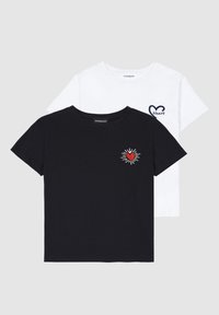 Two t-shirts: one black with a red heart and sunburst embroidery, one white with a heart outline and "Heart" text. Both have short sleeves.